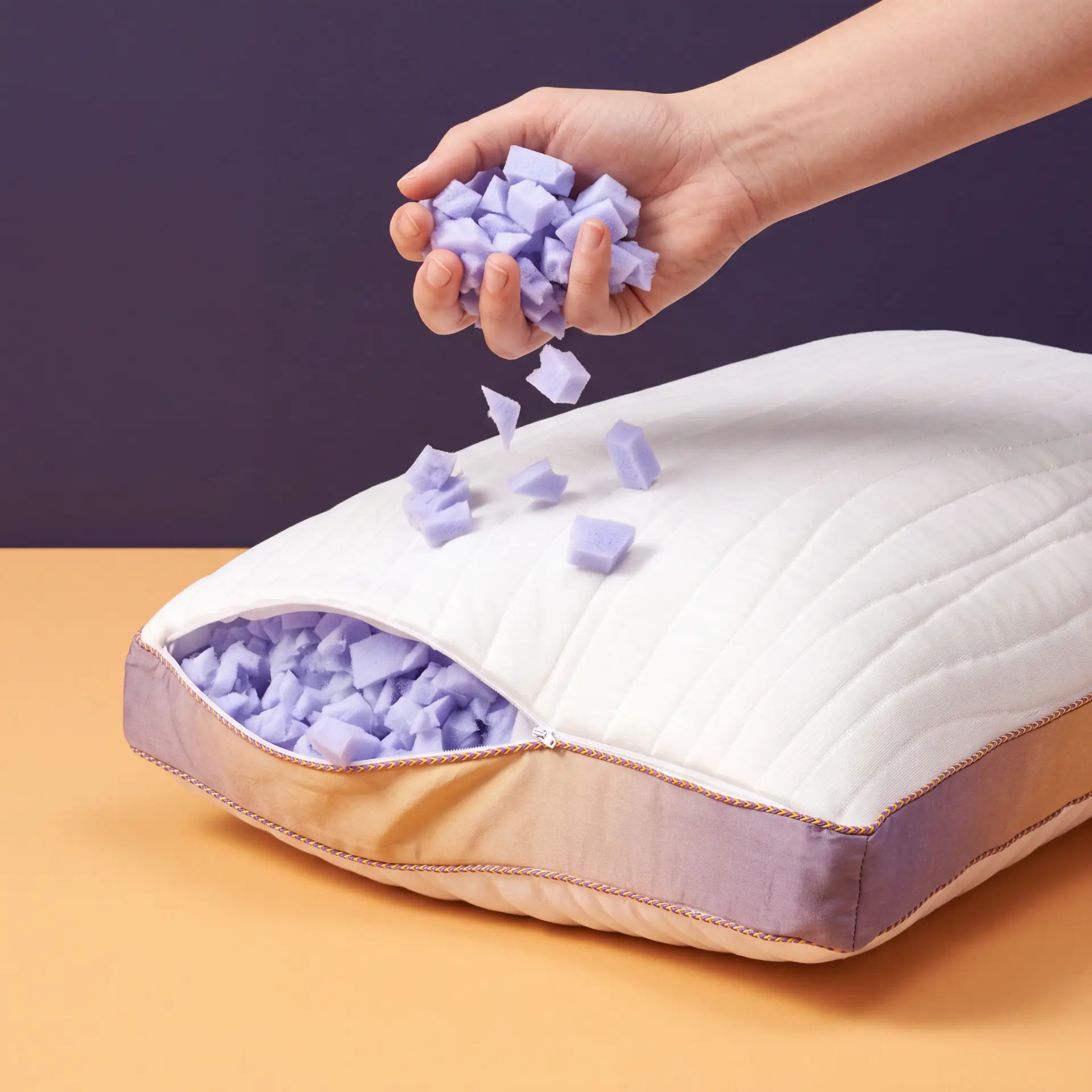 Hand adding a fistful of shredded memory foam back into the pillow