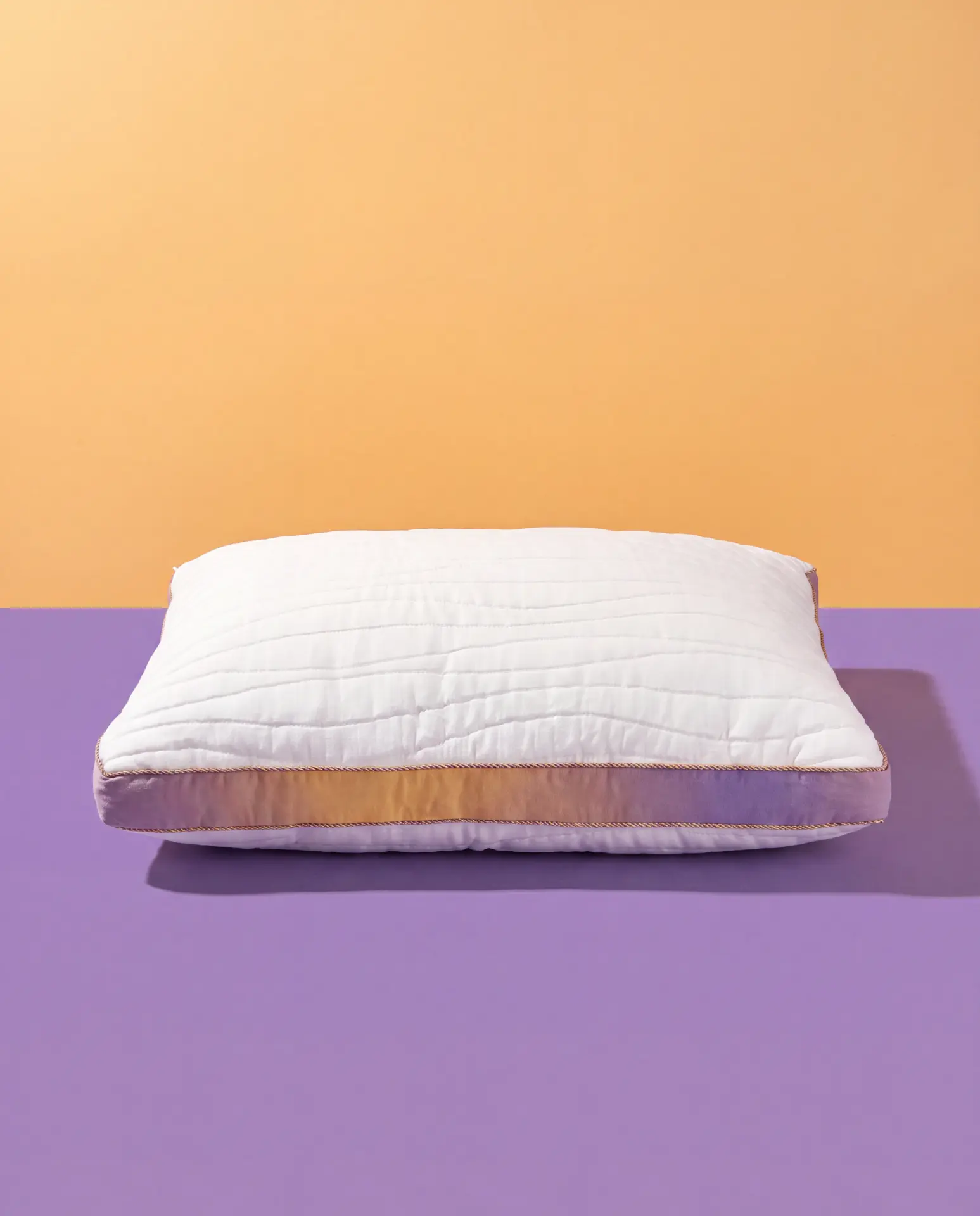 Stigma Sleep pillow on a lavender surface against a gold backdrop